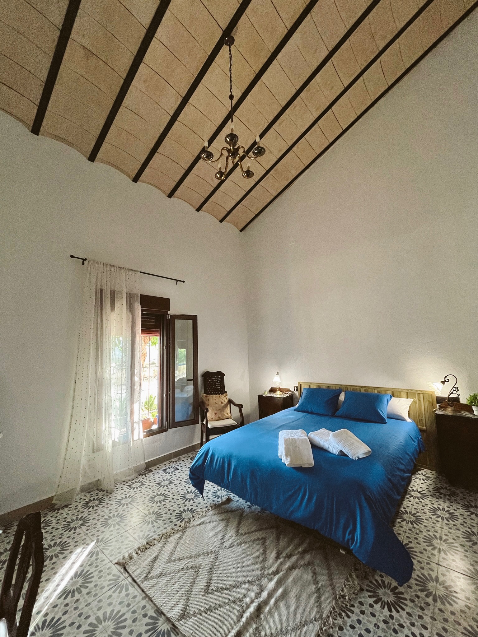 Dormitorio con cama azul y techo de madera de La Antigua Estación
