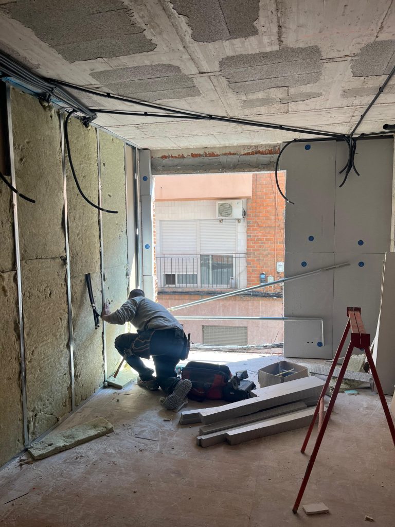Trabajador rehabilitando un interior con instalaciones y aislamiento